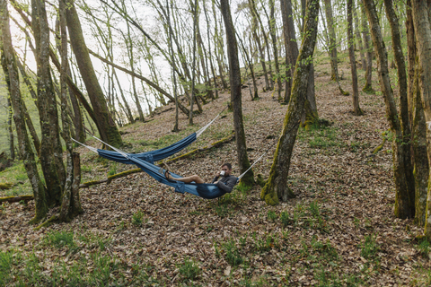 Deutschland, Rheinland-Pfalz, Vulkaneifel, junger Mann in Hängematte liegend im Wald, lizenzfreies Stockfoto