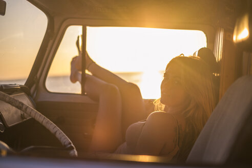 Spanien, Teneriffa, junge Frau in einem Lieferwagen liegend bei Sonnenuntergang - SIPF01881