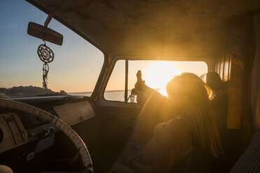 Spanien, Teneriffa, junge Frau in einem Lieferwagen liegend bei Sonnenuntergang - SIPF01884