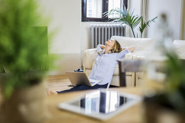 Woman with laptop at home leaning back - GIOF03616