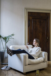 Woman sitting in armchair at home thinking - GIOF03618