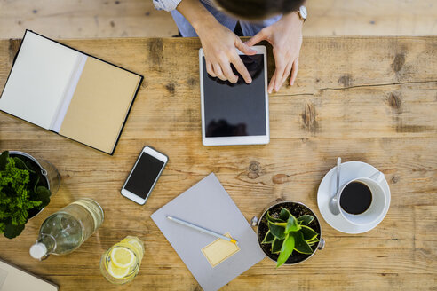 Top view of woman at wooden desk with notebook, cell phone and tablet - GIOF03638