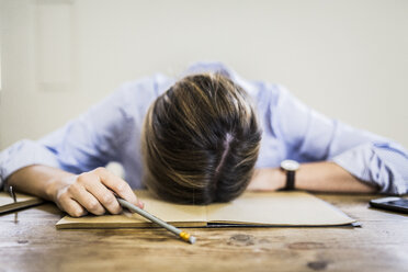 Close-up of woman lying on notebook at desk - GIOF03648