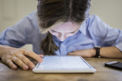 Nahaufnahme einer Frau, die sich über ein Tablet am Schreibtisch beugt - GIOF03649