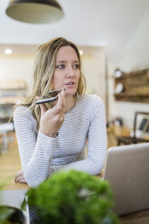 Woman using cell phone at home - GIOF03665