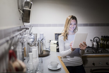 Lächelnde Frau mit Tablet in der Küche - GIOF03679