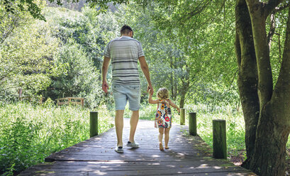 Father walking with his little daughter on a wooden walkway in the countryside - DAPF00846