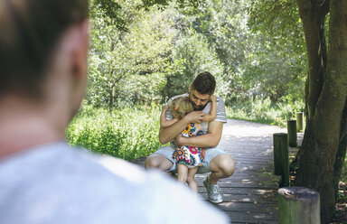 Kleines Mädchen umarmt ihren Vater auf einem Holzsteg auf dem Lande - DAPF00847