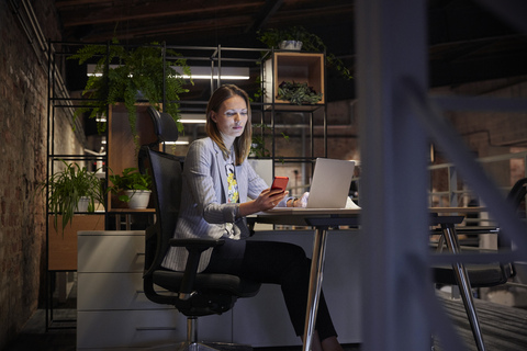 Geschäftsfrau, die in einem modernen Büro arbeitet, mit Laptop und Telefon, lizenzfreies Stockfoto