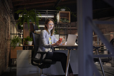 Geschäftsfrau, die in einem modernen Büro arbeitet, mit Laptop und Telefon - WESTF23791