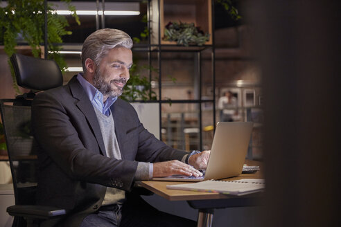 Älterer Geschäftsmann, der in einem modernen Büro arbeitet und einen Laptop benutzt - WESTF23802