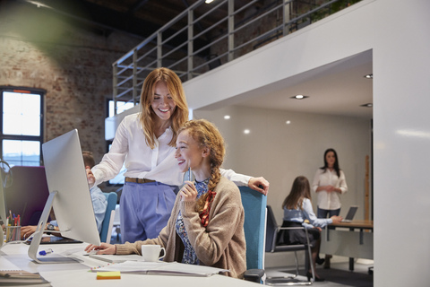 Young woman working in modern creative office, colleague giving advice stock photo