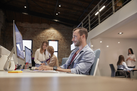 Man working at desk in office, smiling stock photo