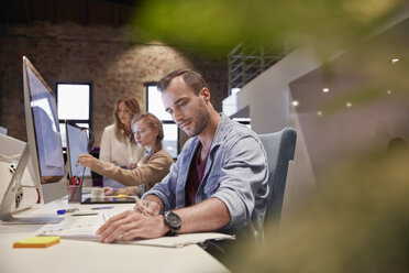 Man working at desk in office, smiling - WESTF23817