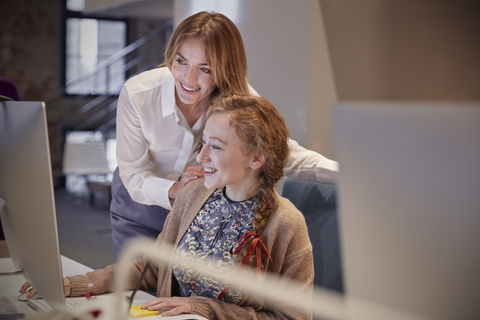 Colleague helping young woman at work stock photo