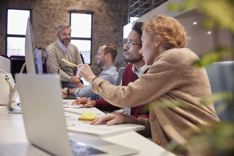 Colleague helping young man at work stock photo