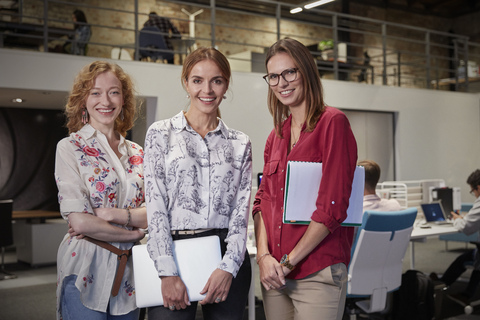 Gruppenporträts von Kolleginnen im Büro, die Akten halten, lizenzfreies Stockfoto