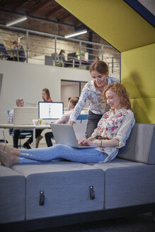 Junge Frau arbeitet in einem modernen, kreativen Büro und benutzt einen Laptop - WESTF23854