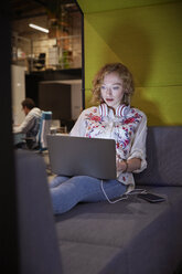 Junge Frau arbeitet in einem modernen, kreativen Büro und benutzt einen Laptop - WESTF23856
