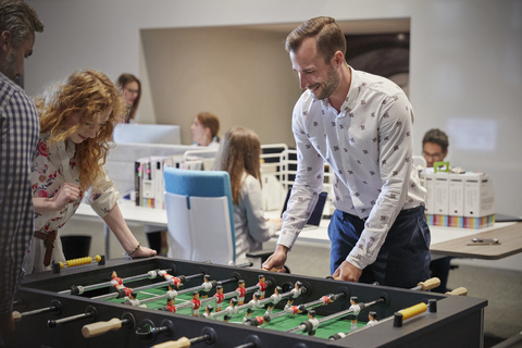 Geschäftsleute im Büro, die eine Pause machen und Tischfußball spielen, lizenzfreies Stockfoto