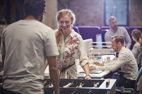 Business people in office taking a break, playing foosball stock photo