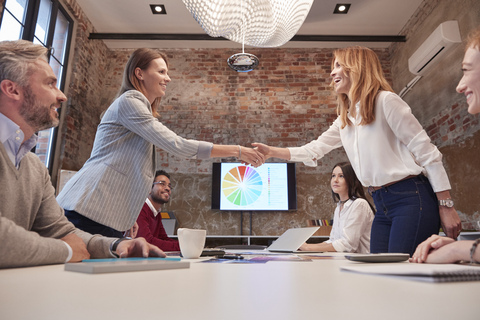 Two businesswomen shaking hands at a presentation stock photo