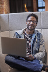 Junger Mann, der in einem kreativen Start-up-Unternehmen arbeitet und einen Laptop benutzt - WESTF23891