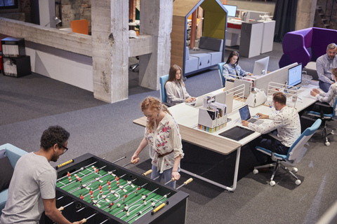 Geschäftsleute im Büro, die eine Pause machen und Tischfußball spielen, lizenzfreies Stockfoto
