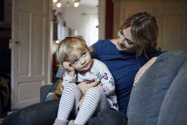 Mutter und kleine Tochter sitzen zusammen auf der Couch zu Hause - RBF06167