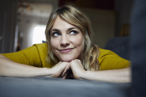 Portrait of woman lying on the couch at home thinking stock photo