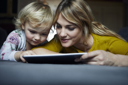 Porträt von Mutter und kleiner Tochter, die zu Hause ein Tablet benutzen - RBF06184