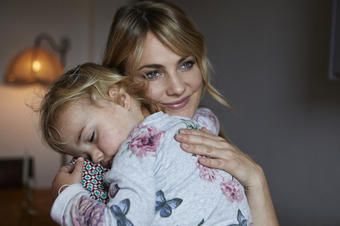 Portrait of happy mother holding sleeping little daughter on her arms stock photo