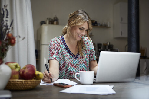 Portrait of laughing woman working on laptop at home - RBF06190