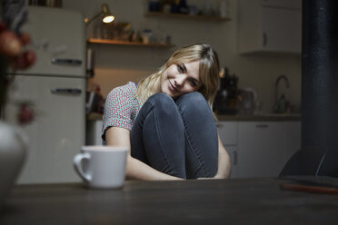 Porträt einer lächelnden Frau, die in der Küche sitzt - RBF06195