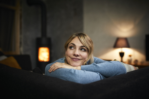 Portrait of smiling woman relaxing on couch at home in the evening stock photo