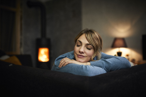 Porträt einer Frau, die sich abends zu Hause auf der Couch entspannt, lizenzfreies Stockfoto