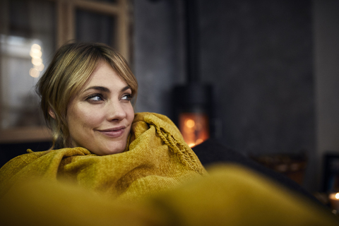 Portrait of smiling woman relaxing on couch at home in the evening stock photo