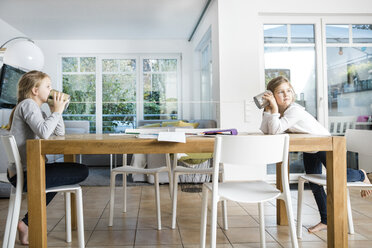 Two girls using tin can phone at table - MOEF00521