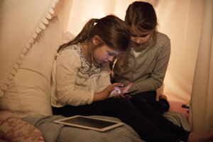 Zwei Mädchen mit Handy und Tablet im Kinderzimmer - MOEF00555