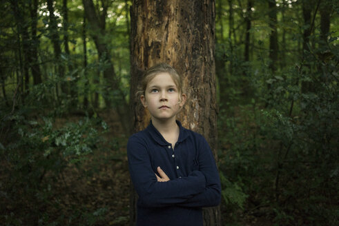 Porträt eines selbstbewussten Mädchens, das an einem Baumstamm im Wald steht - MOEF00568