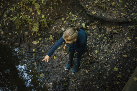 Mädchen in einem Wald an einem Teich stehend und mit dem Finger zeigend, lizenzfreies Stockfoto