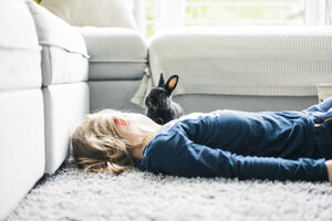 Mädchen liegend mit Hase im Wohnzimmer - MOEF00577