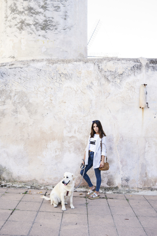 Junge Frau mit ihrem Hund auf dem Bürgersteig, lizenzfreies Stockfoto