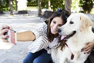 Glückliche junge Frau macht Selfie mit ihrem Hund - IGGF00323