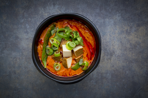 Schüssel mit rotem Thai-Curry mit Zuckerschoten, Karotten, Paprika, Frühlingszwiebeln und geräuchertem Tofu, lizenzfreies Stockfoto