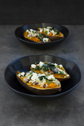 Filled sweet potato with spinach, red onion, couscous, feta and coriander stock photo