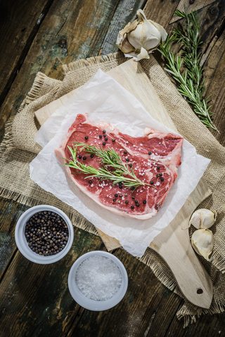 Rohes Beefsteak mit Rosmarin, Salz und Pfeffer, lizenzfreies Stockfoto