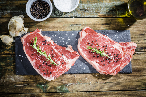 Rohes Beefsteak mit Rosmarin, Salz und Pfeffer, lizenzfreies Stockfoto