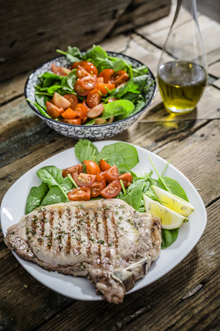 Roasted beefsteak with rosemary, spinach salad with tomato, lemon stock photo