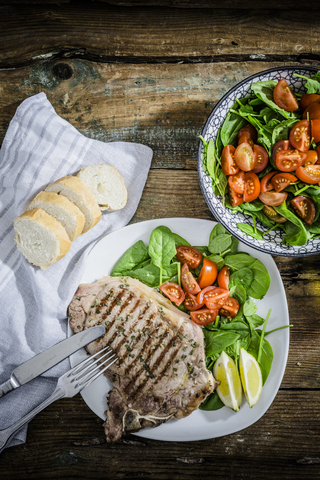 Roasted beefsteak with rosemary, spinach salad with tomato, lemon stock photo